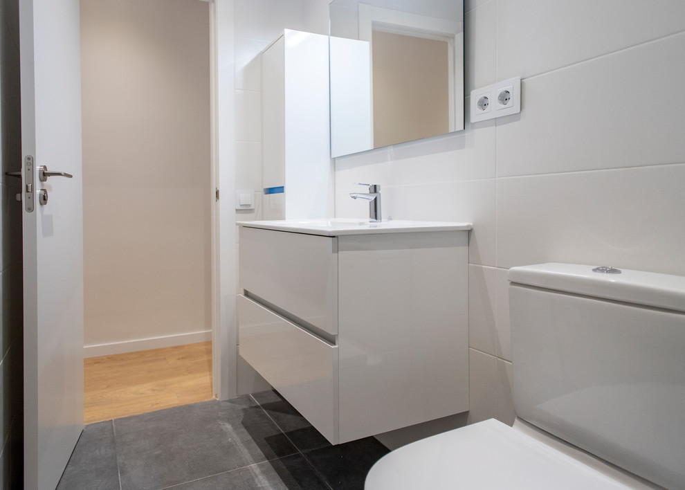 Immagine di una stanza da bagno padronale design di medie dimensioni con ante bianche, doccia a filo pavimento, WC monopezzo, piastrelle beige, pavimento grigio, porta doccia scorrevole e top bianco