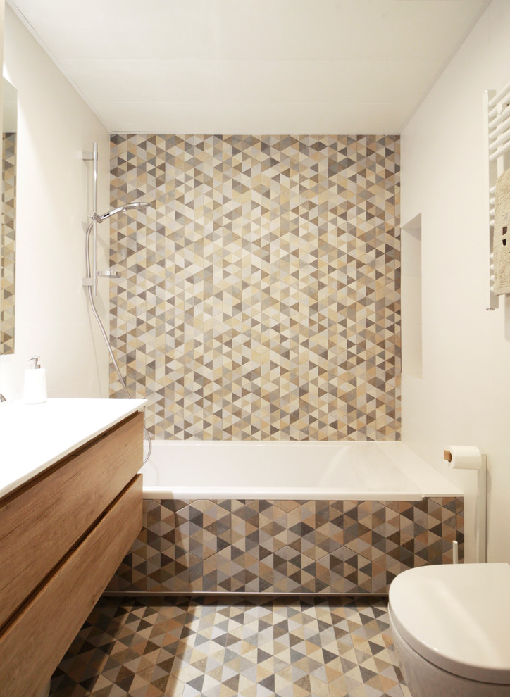 Idée de décoration pour une petite salle de bain design en bois brun avec un placard à porte plane, une baignoire en alcôve, un combiné douche/baignoire, un carrelage multicolore, des carreaux de céramique, un mur blanc, un sol multicolore, WC suspendus, un sol en carrelage de céramique, un plan de toilette blanc et un lavabo encastré.
