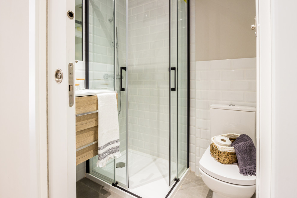 Идея дизайна: маленькая ванная комната в современном стиле с светлыми деревянными фасадами, угловым душем, белой плиткой, керамической плиткой, плоскими фасадами, унитазом-моноблоком, бежевыми стенами, душевой кабиной, консольной раковиной, бежевым полом, душем с раздвижными дверями и белой столешницей для на участке и в саду