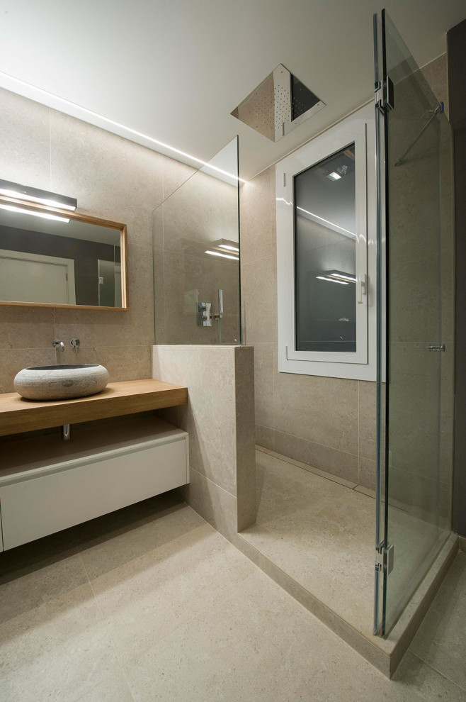 Inredning av ett modernt mellanstort beige beige badrum med dusch, med släta luckor, beige skåp, en dusch i en alkov, beige kakel, porslinskakel, klinkergolv i porslin, ett fristående handfat, träbänkskiva, beiget golv och dusch med gångjärnsdörr