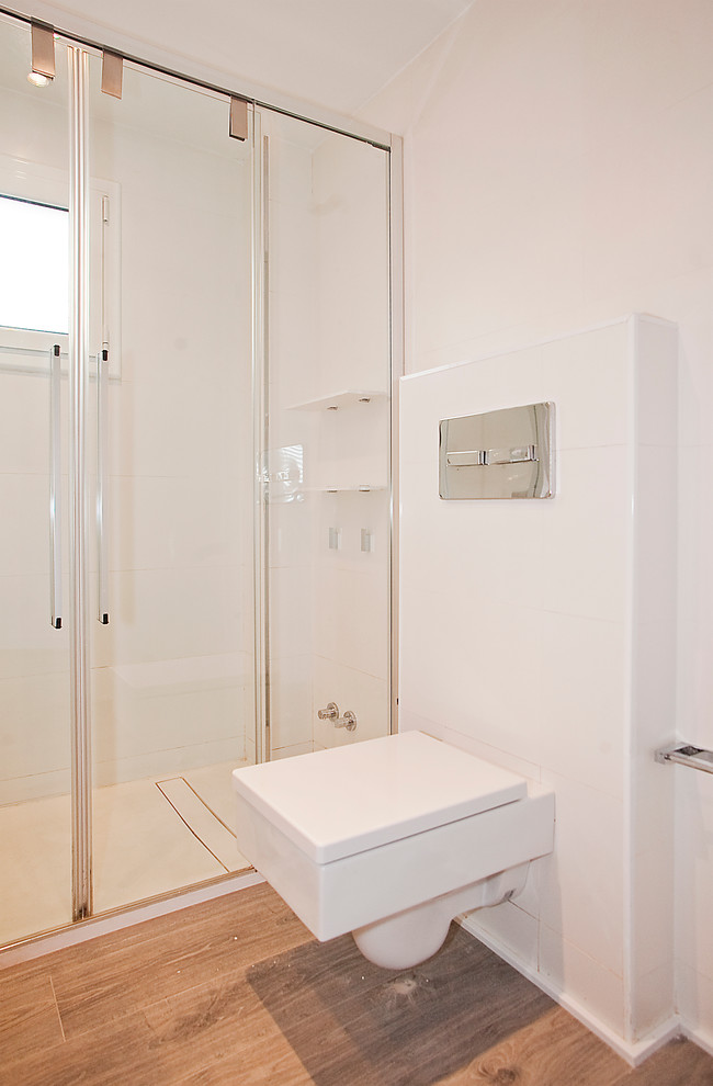 Photo of a medium sized contemporary ensuite bathroom in Barcelona with white cabinets, an alcove shower, a one-piece toilet, white tiles, white walls, dark hardwood flooring and a trough sink.