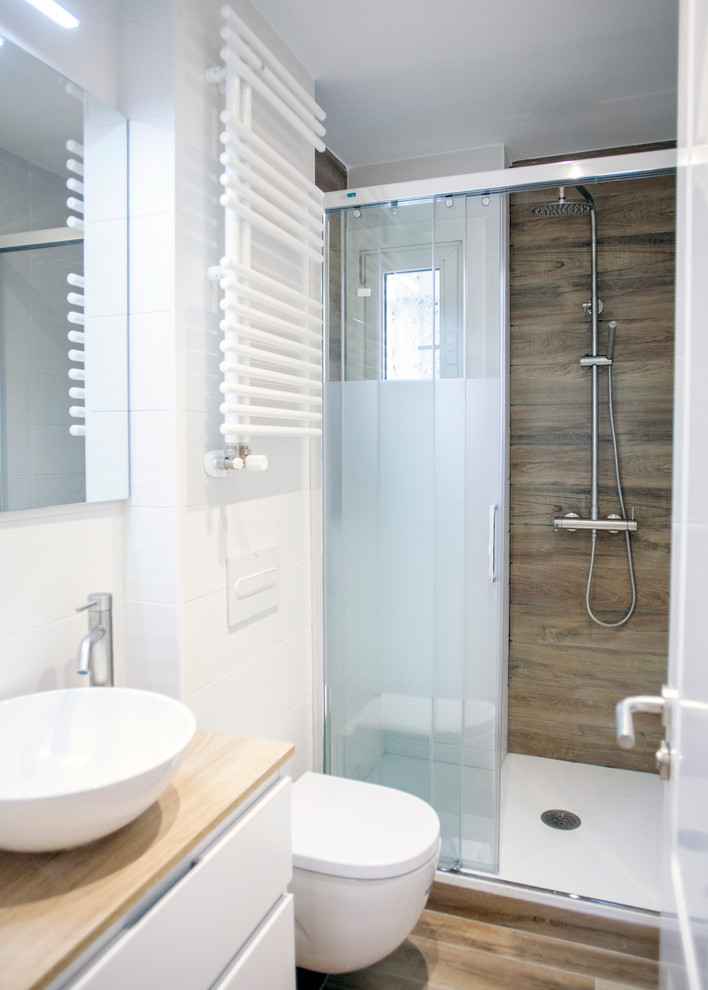 На фото: главная ванная комната среднего размера в современном стиле с белыми фасадами, душем без бортиков, унитазом-моноблоком, белой плиткой, белыми стенами, настольной раковиной, коричневым полом и душем с раздвижными дверями