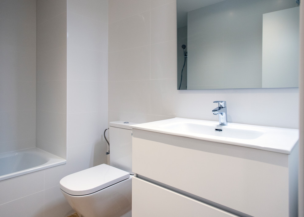 Inredning av ett modernt mellanstort vit vitt en-suite badrum, med vita skåp, ett badkar i en alkov, en kantlös dusch, en toalettstol med hel cisternkåpa, vit kakel, tunnelbanekakel, vita väggar och dusch med skjutdörr