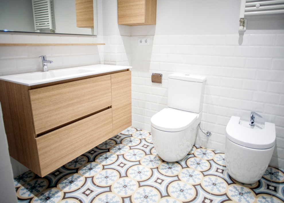 Modern inredning av ett mellanstort en-suite badrum, med skåp i ljust trä, ett badkar i en alkov, en kantlös dusch, en toalettstol med separat cisternkåpa, vita väggar, ett fristående handfat, blått golv och med dusch som är öppen