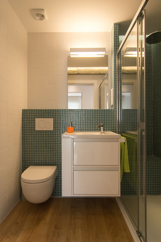 Imagen de cuarto de baño actual de tamaño medio con armarios con paneles lisos, puertas de armario blancas, sanitario de pared, paredes blancas, suelo de madera en tonos medios, aseo y ducha y lavabo integrado
