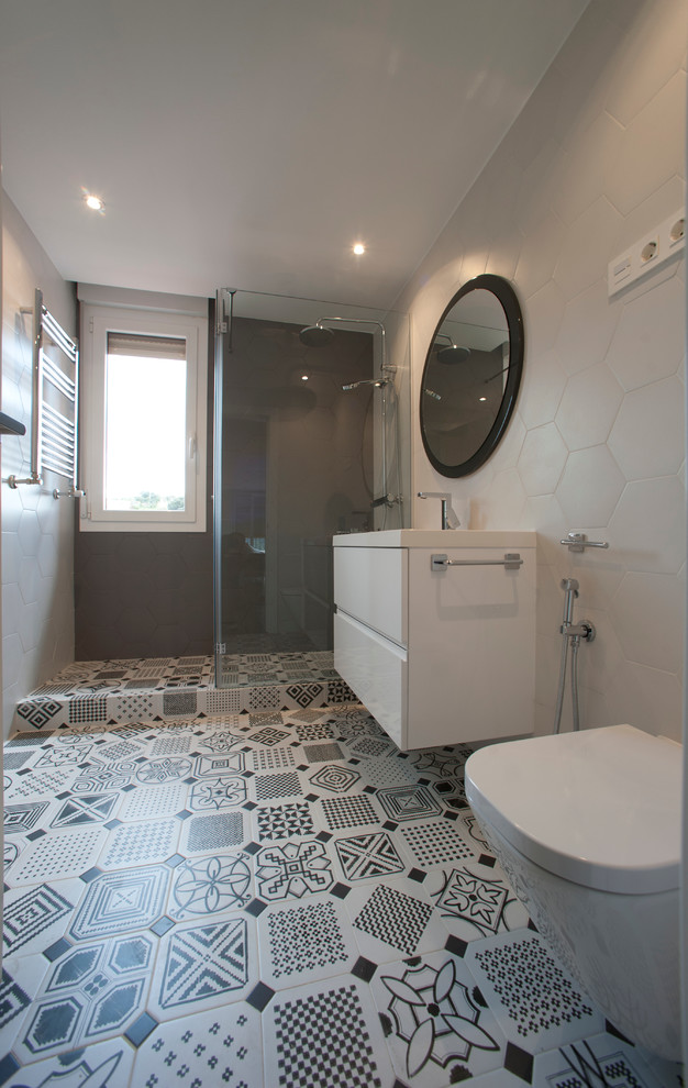 Diseño de cuarto de baño moderno de tamaño medio con armarios con paneles lisos, puertas de armario blancas, ducha esquinera, sanitario de pared, paredes grises, suelo de baldosas de cerámica, aseo y ducha y lavabo integrado