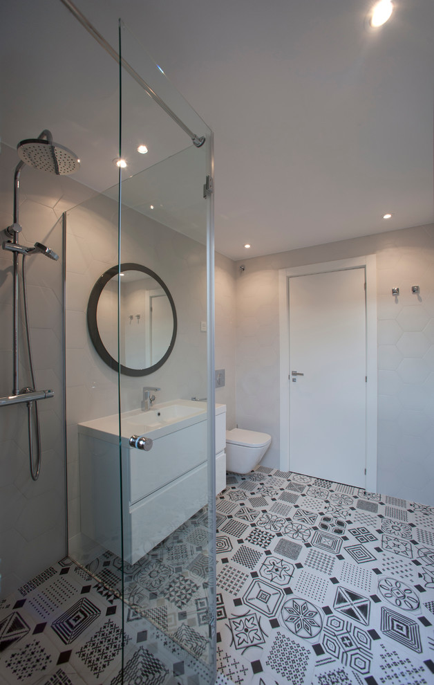 Diseño de cuarto de baño minimalista de tamaño medio con ducha esquinera, sanitario de pared, paredes grises, suelo de baldosas de cerámica, aseo y ducha, lavabo integrado, armarios con paneles lisos y puertas de armario blancas