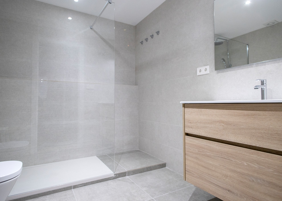 Medium sized contemporary ensuite bathroom in Barcelona with medium wood cabinets, a built-in shower, a two-piece toilet, grey tiles, ceramic tiles, ceramic flooring, grey floors, a hinged door and white worktops.