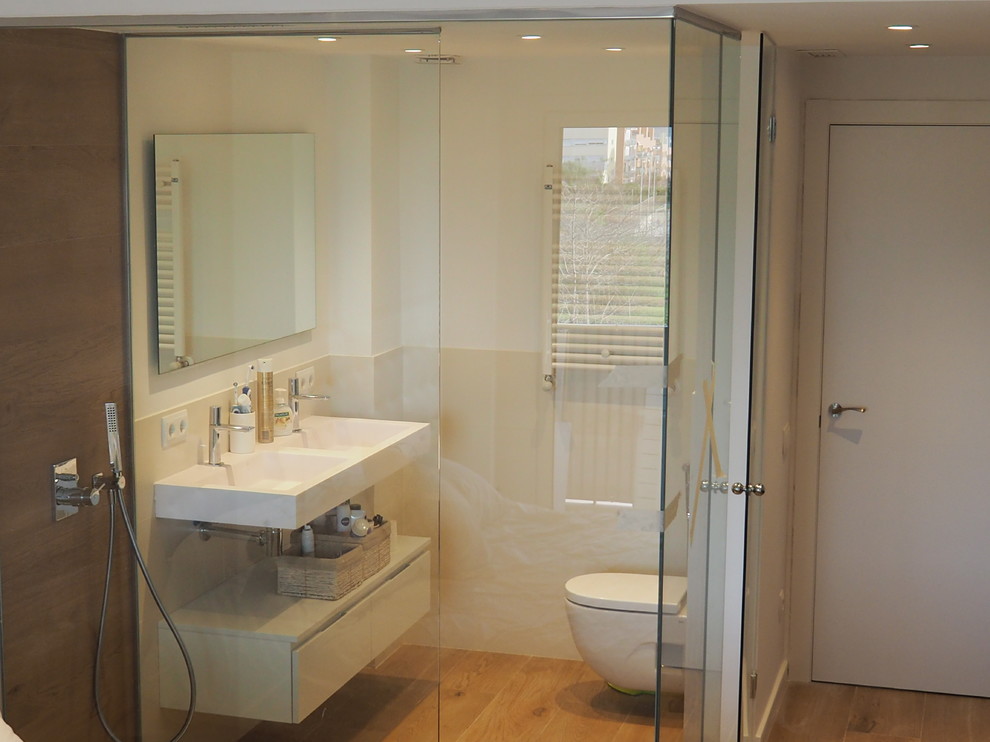 Mittelgroßes Modernes Badezimmer En Suite mit weißen Schränken, bodengleicher Dusche, Toilette mit Aufsatzspülkasten, beigen Fliesen, weißer Wandfarbe, braunem Holzboden und Trogwaschbecken in Barcelona