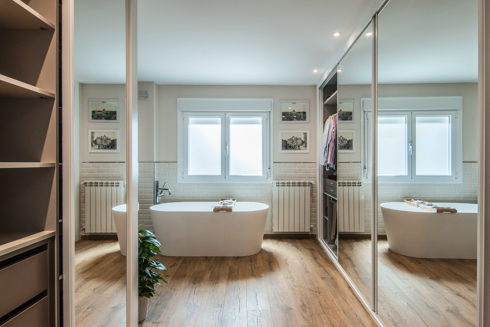 Imagen de cuarto de baño principal grande con bañera exenta, paredes blancas, suelo laminado, suelo beige y ducha con puerta con bisagras