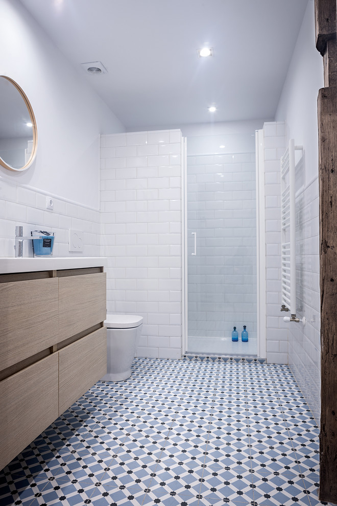 Mittelgroßes Maritimes Duschbad mit flächenbündigen Schrankfronten, hellbraunen Holzschränken, Duschnische, Toilette mit Aufsatzspülkasten, weißer Wandfarbe und integriertem Waschbecken in Bilbao