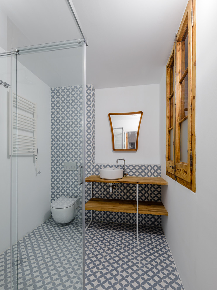 Idéer för att renovera ett mellanstort industriellt brun brunt badrum med dusch, med en kantlös dusch, keramikplattor, träbänkskiva, öppna hyllor, skåp i mellenmörkt trä och dusch med skjutdörr