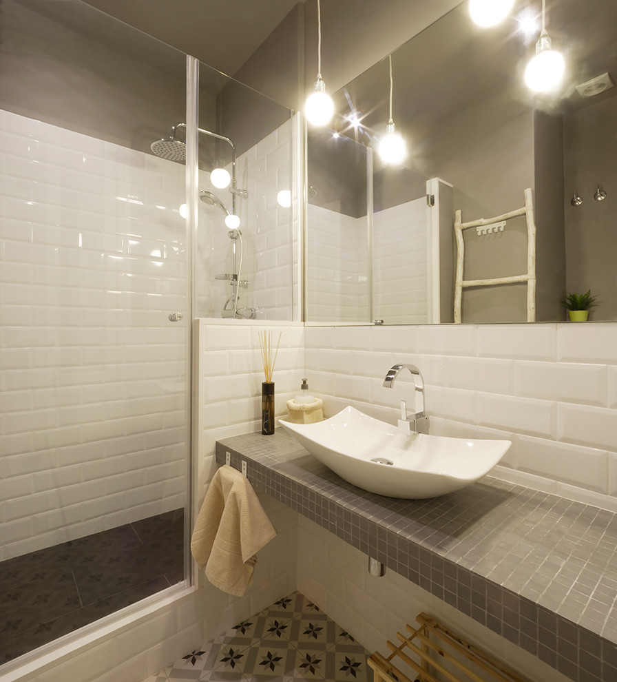 Bild på ett litet funkis en-suite badrum, med en dusch i en alkov, ett fristående handfat, dusch med gångjärnsdörr, öppna hyllor, en toalettstol med separat cisternkåpa, grå kakel, keramikplattor, grå väggar, cementgolv, kaklad bänkskiva och flerfärgat golv