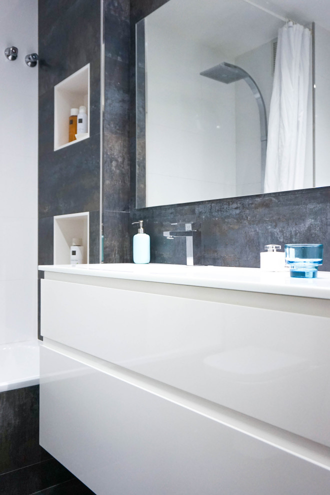 На фото: главная ванная комната среднего размера в современном стиле с плоскими фасадами, белыми фасадами, накладной ванной, душем над ванной, унитазом-моноблоком, черной плиткой, керамической плиткой, белыми стенами, полом из керамогранита, монолитной раковиной, столешницей из искусственного камня, черным полом, открытым душем, белой столешницей, нишей, тумбой под одну раковину и подвесной тумбой