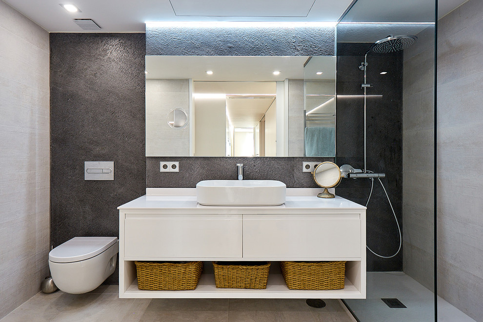 Ejemplo de cuarto de baño actual con puertas de armario blancas, ducha a ras de suelo, baldosas y/o azulejos grises, paredes negras, aseo y ducha, lavabo sobreencimera y encimeras blancas