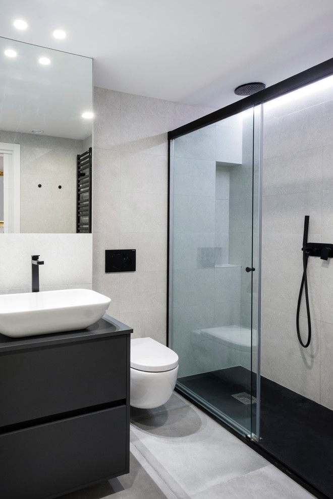 Réalisation d'une salle de bain design de taille moyenne pour enfant avec un placard à porte plane, des portes de placard noires, une douche ouverte, WC suspendus, un carrelage gris et un plan de toilette noir.