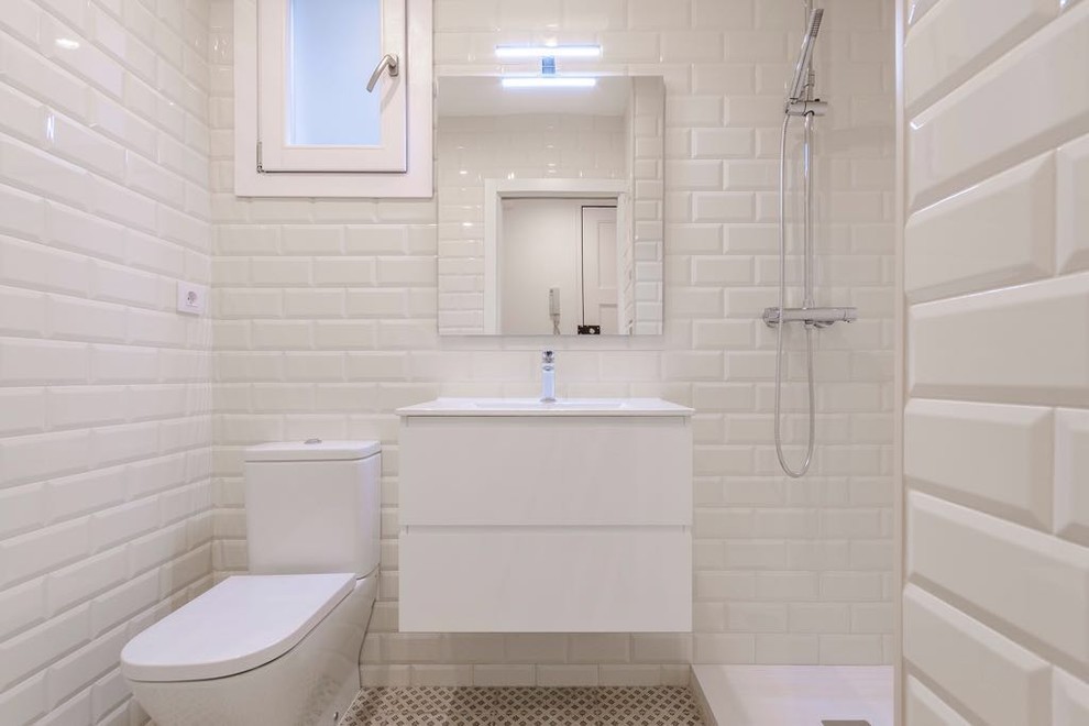 Exempel på ett litet 60 tals en-suite badrum, med släta luckor, våtrum, en toalettstol med separat cisternkåpa, vit kakel, stickkakel, vita väggar, ett integrerad handfat, bänkskiva i akrylsten, beiget golv och dusch med gångjärnsdörr