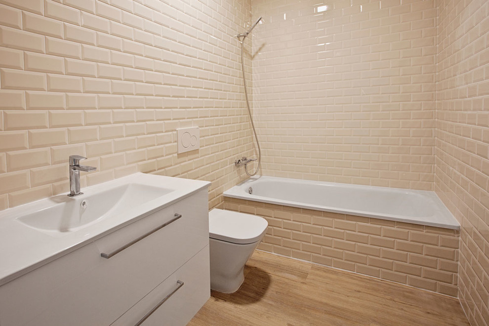 Immagine di una stanza da bagno industriale di medie dimensioni con ante lisce, ante bianche, WC sospeso, piastrelle beige, piastrelle in ceramica, pareti beige, parquet chiaro e lavabo da incasso