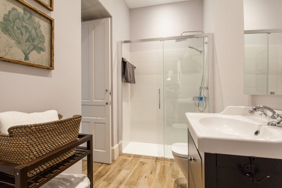 Immagine di una stanza da bagno con doccia minimalista di medie dimensioni con consolle stile comò, ante nere, doccia alcova, WC a due pezzi, pareti bianche, pavimento in legno massello medio e lavabo integrato