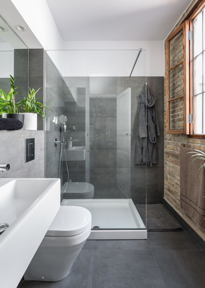 Modern inredning av ett mellanstort badrum med dusch, med en hörndusch, en toalettstol med hel cisternkåpa, grå väggar, klinkergolv i keramik och ett avlångt handfat