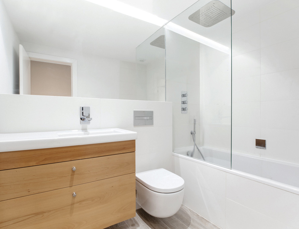 Modelo de cuarto de baño principal minimalista de tamaño medio con armarios con paneles lisos, puertas de armario de madera oscura, bañera empotrada, combinación de ducha y bañera, sanitario de pared y lavabo integrado