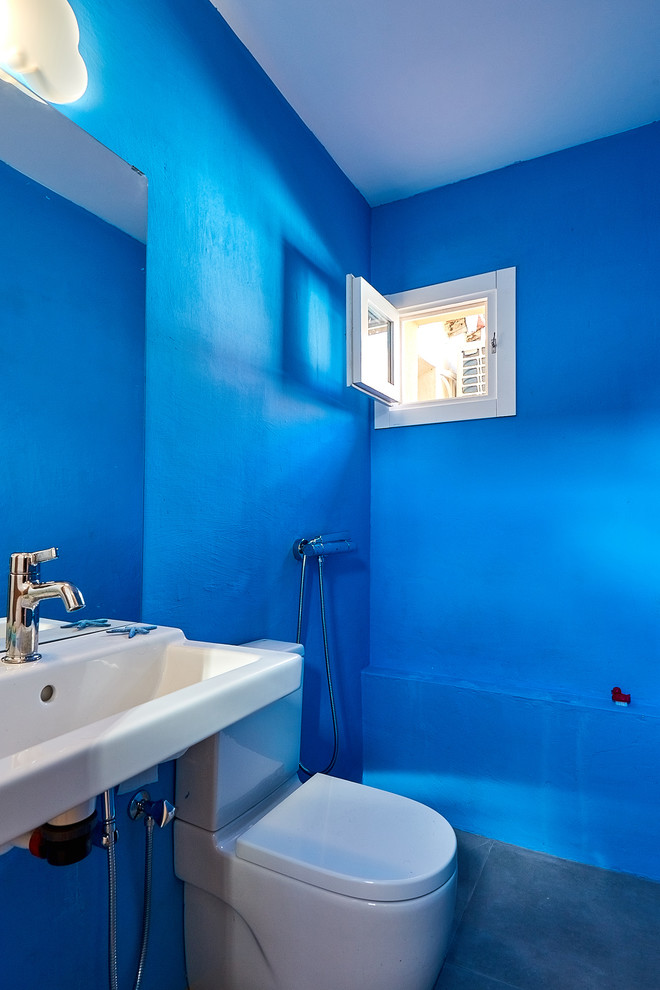 Foto de cuarto de baño mediterráneo con sanitario de dos piezas, paredes azules, lavabo suspendido y suelo gris