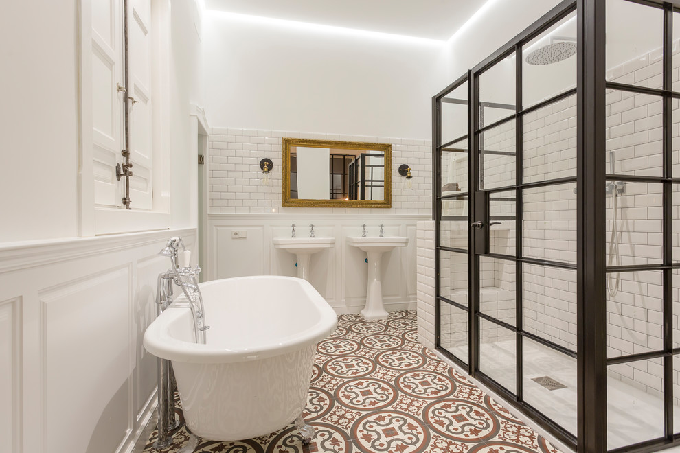 На фото: главная ванная комната среднего размера в средиземноморском стиле с ванной на ножках, душем в нише, белой плиткой, плиткой кабанчик, белыми стенами, полом из керамической плитки, раковиной с пьедесталом, разноцветным полом и душем с распашными дверями с