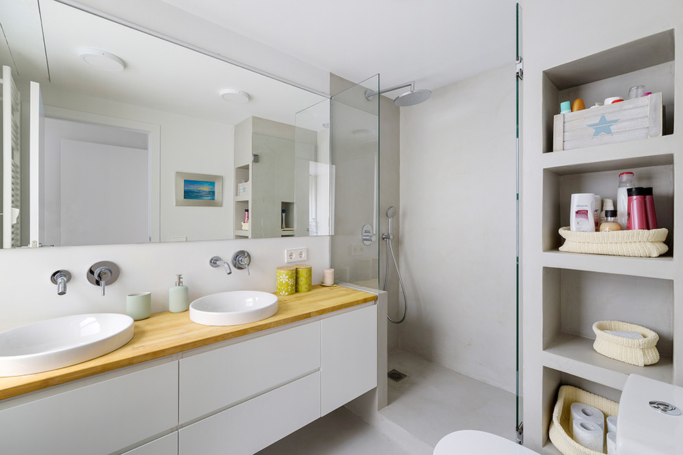 Modern inredning av ett mellanstort beige beige badrum med dusch, med släta luckor, vita skåp, en dusch i en alkov, ett fristående handfat, träbänkskiva, dusch med gångjärnsdörr, vita väggar och grått golv