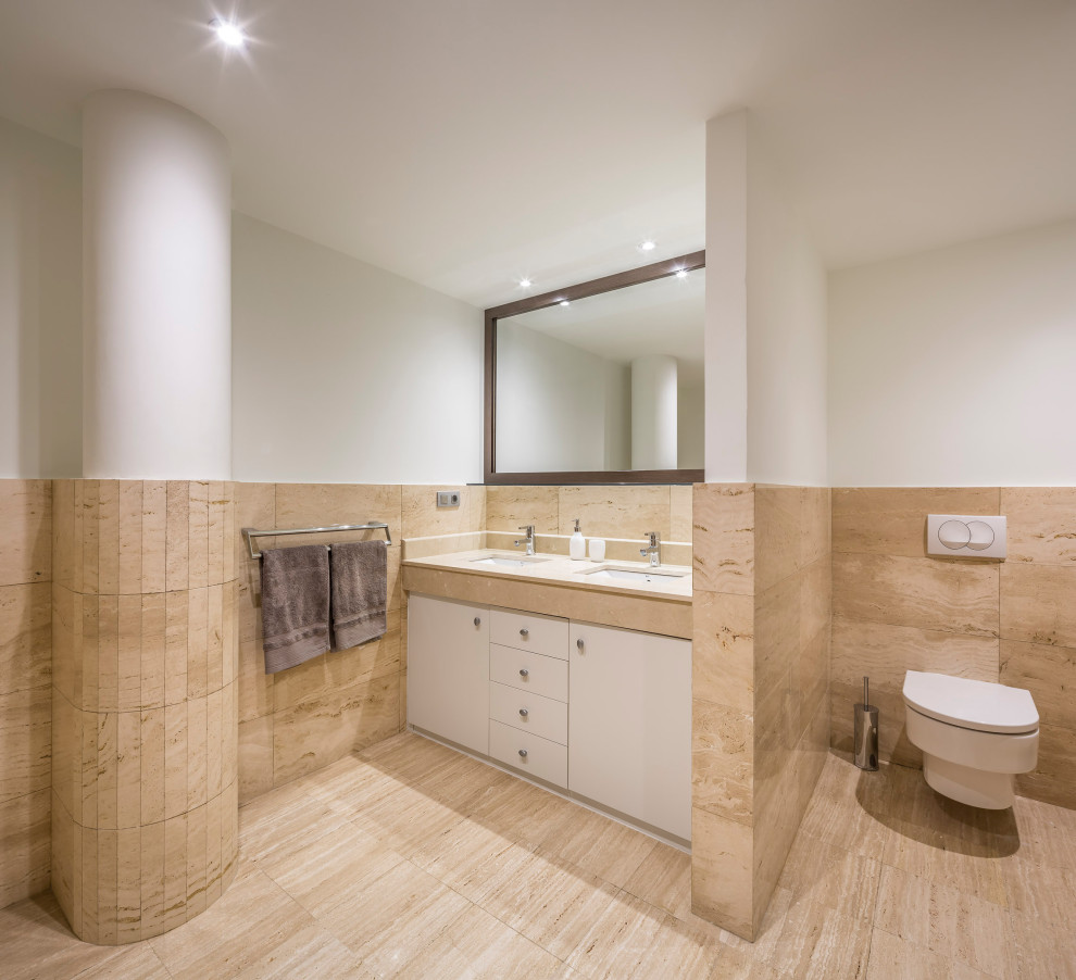 Großes Modernes Badezimmer En Suite mit flächenbündigen Schrankfronten, Einbaubadewanne, Wandtoilette, Travertinfliesen, beiger Wandfarbe, Marmor-Waschbecken/Waschtisch, Falttür-Duschabtrennung und eingebautem Waschtisch in Alicante-Costa Blanca