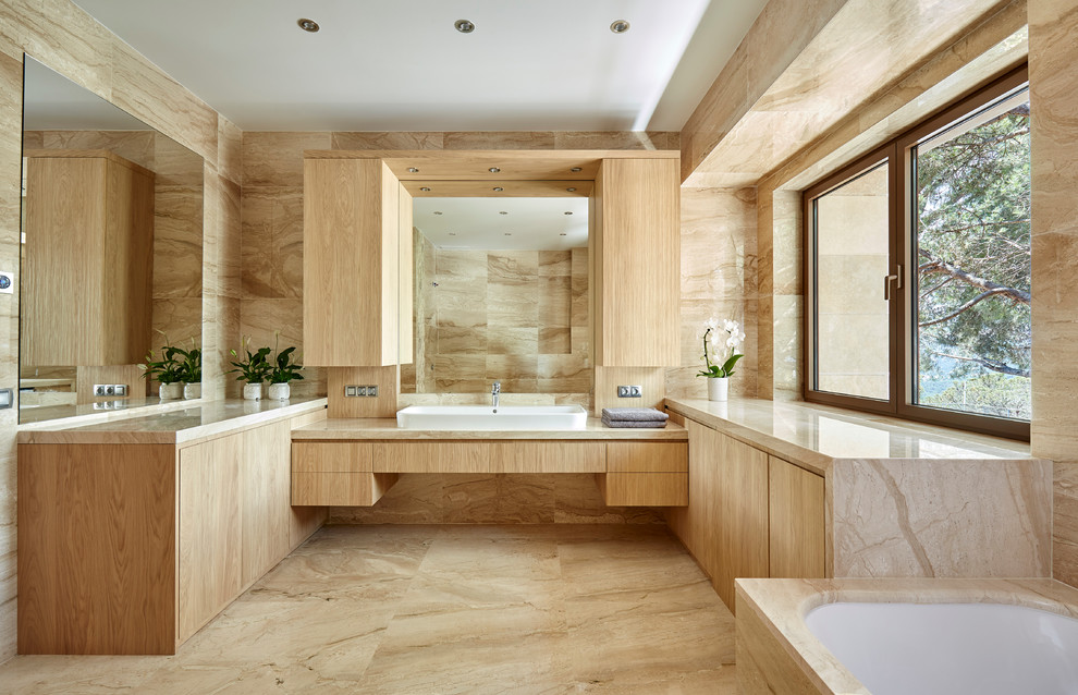 Modelo de cuarto de baño principal contemporáneo grande con armarios con paneles lisos, lavabo sobreencimera, puertas de armario de madera clara, bañera encastrada sin remate y paredes beige