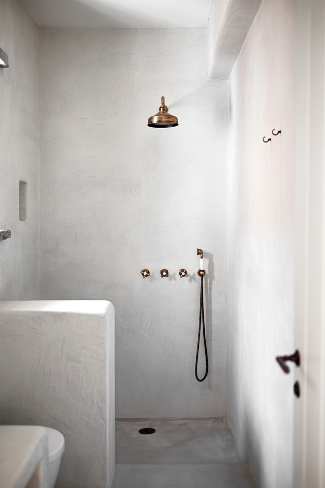 Diseño de cuarto de baño mediterráneo con ducha abierta, paredes blancas, suelo de cemento, aseo y ducha, encimera de mármol, suelo gris, ducha abierta y microcemento