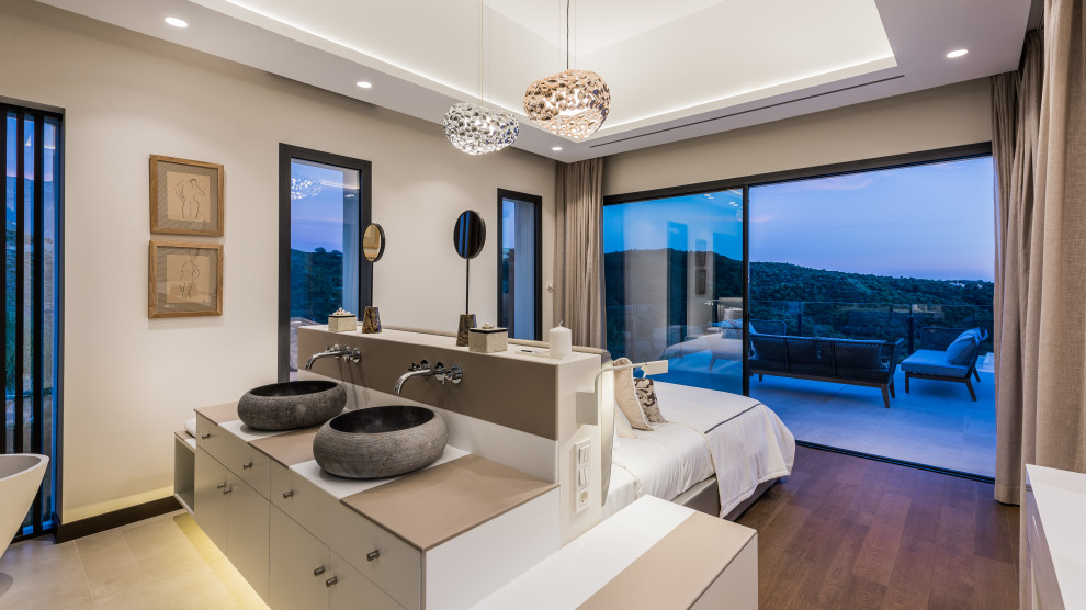 Modern inredning av ett brun brunt en-suite badrum, med släta luckor, vita skåp, ett fristående badkar, beige väggar, mörkt trägolv, ett fristående handfat och brunt golv