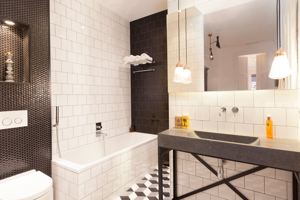 Cette image montre une salle de bain principale design de taille moyenne avec une baignoire en alcôve, un combiné douche/baignoire, WC à poser, un carrelage noir et blanc, des carreaux de céramique, un mur blanc, un sol en carrelage de céramique et un lavabo intégré.