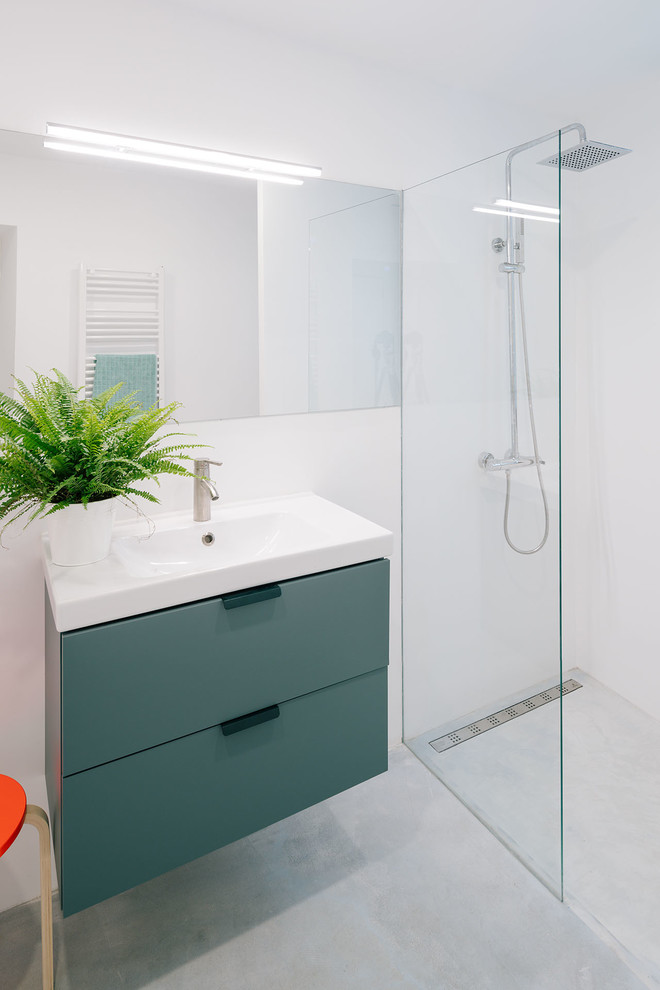 Inredning av ett modernt badrum, med släta luckor, blå skåp, en kantlös dusch, vita väggar och ett väggmonterat handfat