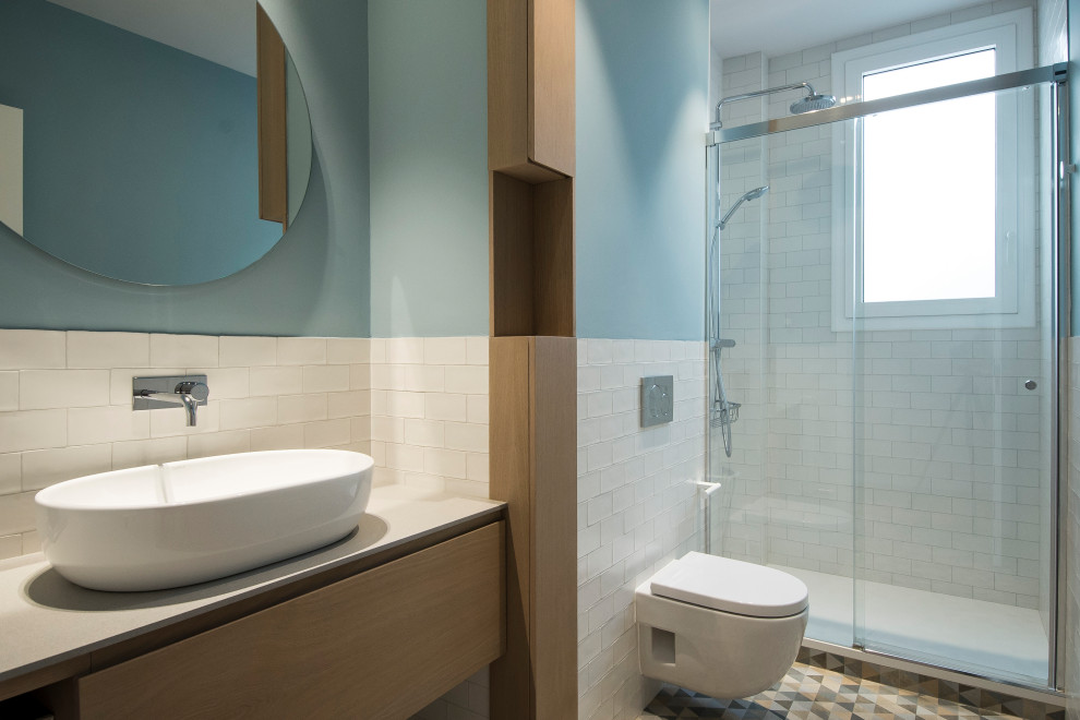 Imagen de cuarto de baño único y flotante contemporáneo pequeño con armarios con paneles lisos, puertas de armario azules, sanitario de pared, baldosas y/o azulejos blancos, baldosas y/o azulejos de cemento, paredes azules, suelo de baldosas de cerámica, aseo y ducha, lavabo sobreencimera, encimera de mármol y encimeras grises