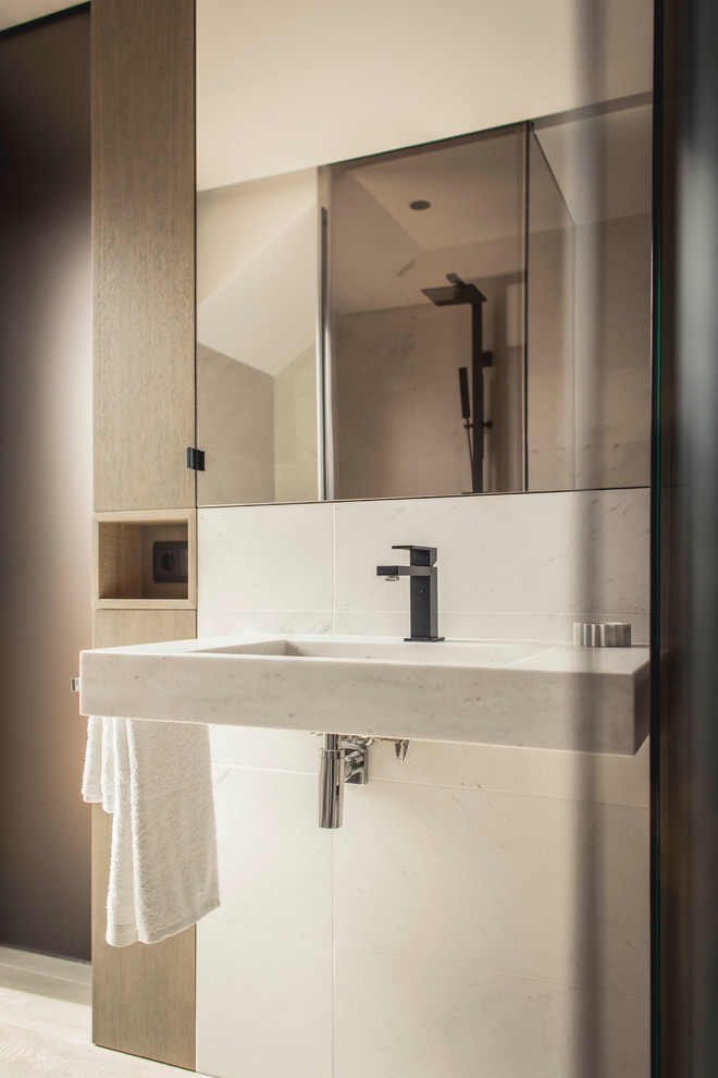 Inspiration för mellanstora moderna en-suite badrum, med möbel-liknande, skåp i mellenmörkt trä, en kantlös dusch, en vägghängd toalettstol, vit kakel, vita väggar, mellanmörkt trägolv, ett väggmonterat handfat och marmorbänkskiva