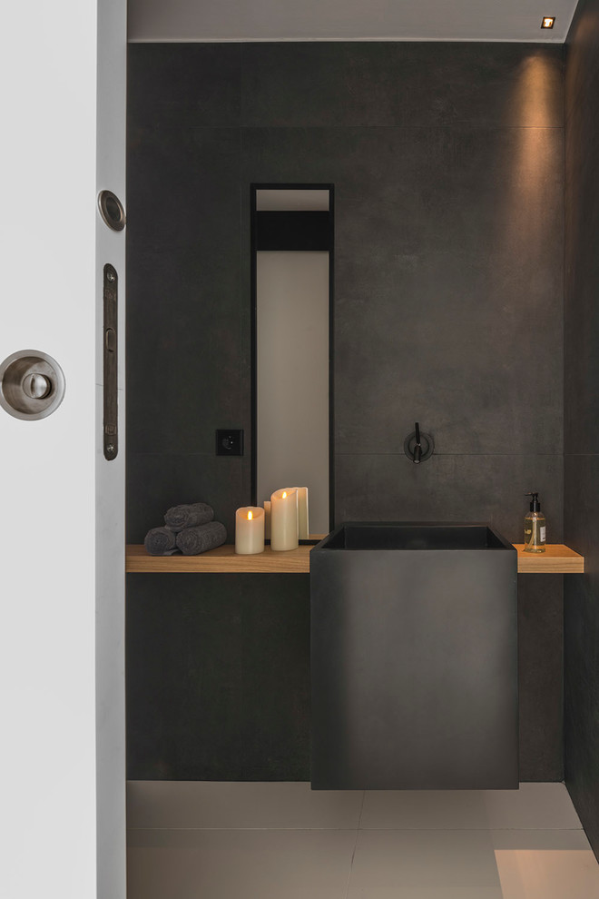 Idée de décoration pour une salle de bain design de taille moyenne avec un placard sans porte, des portes de placard noires, une douche ouverte, un carrelage noir, un lavabo suspendu, un plan de toilette en acier inoxydable et un plan de toilette noir.