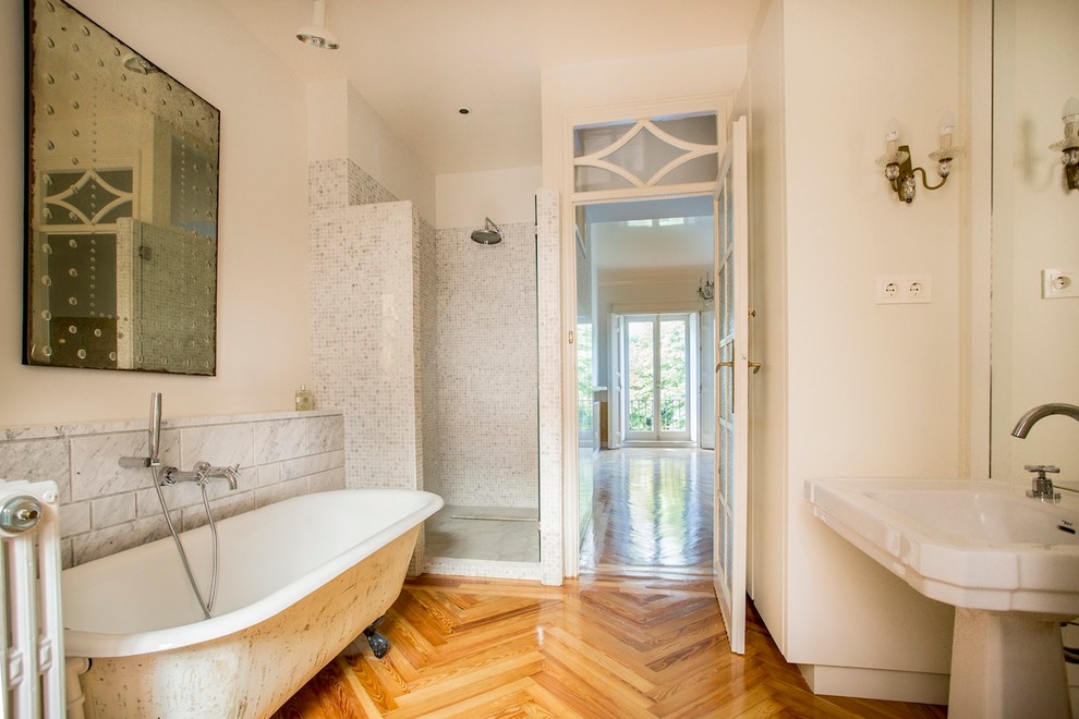 Foto på ett mellanstort vintage en-suite badrum, med ett piedestal handfat, ett badkar med tassar, en dusch i en alkov, vita väggar, mellanmörkt trägolv, svart och vit kakel och stenkakel