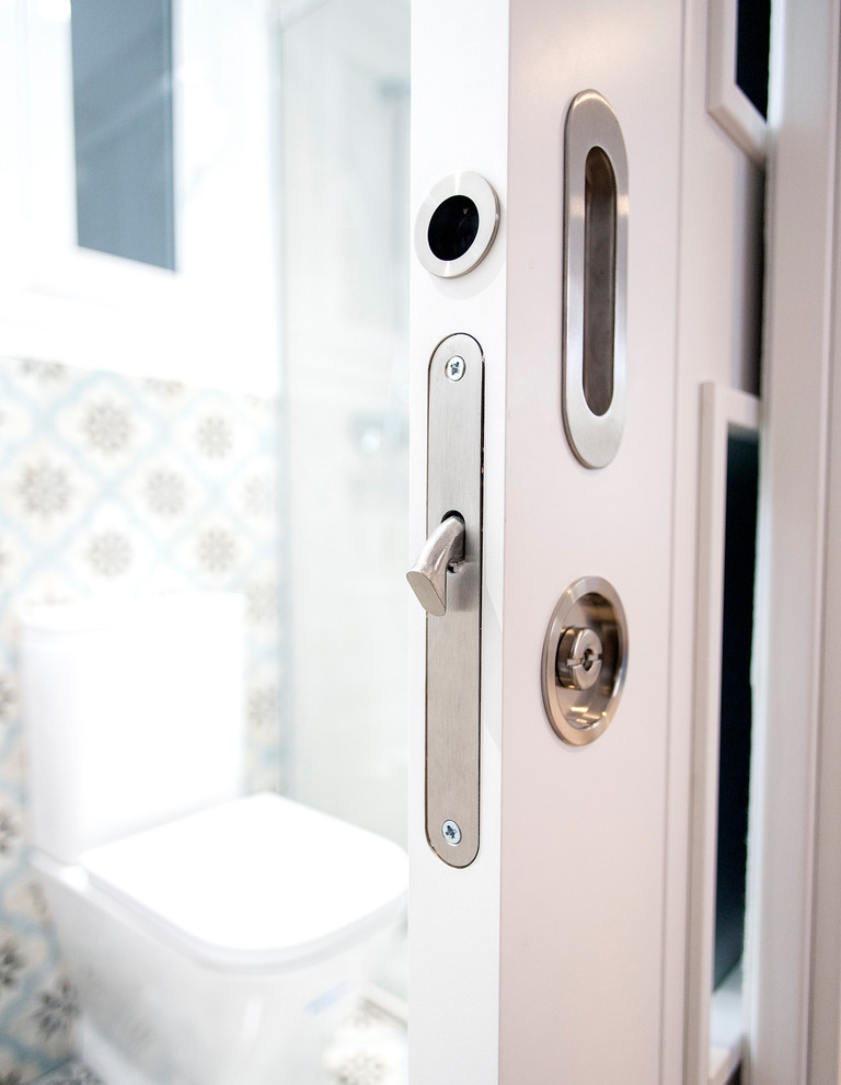 Inspiration för mellanstora moderna vitt en-suite badrum, med vita skåp, en kantlös dusch, en toalettstol med hel cisternkåpa, flerfärgad kakel, keramikplattor, vita väggar, klinkergolv i keramik, flerfärgat golv och dusch med skjutdörr