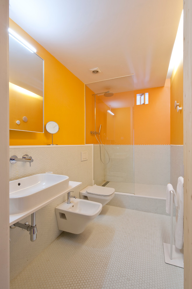 Foto på ett mellanstort funkis badrum med dusch, med en dusch i en alkov, en vägghängd toalettstol, orange väggar och ett väggmonterat handfat