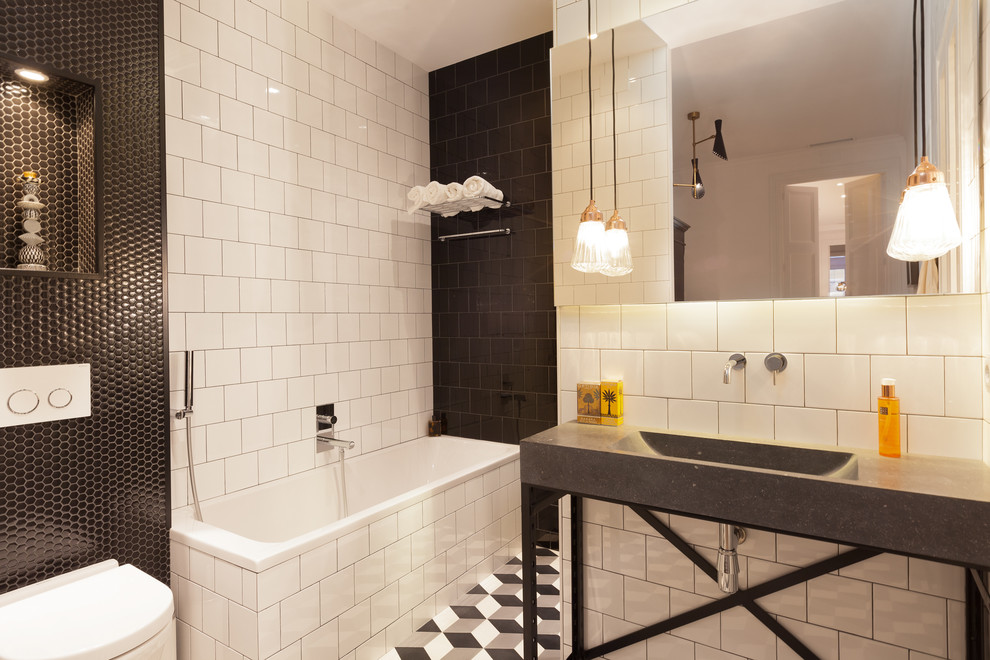 Bild på ett litet funkis en-suite badrum, med mosaik, vita väggar, mosaikgolv, svart och vit kakel, ett hörnbadkar, en dusch/badkar-kombination, en vägghängd toalettstol, ett konsol handfat, bänkskiva i betong, flerfärgat golv och med dusch som är öppen