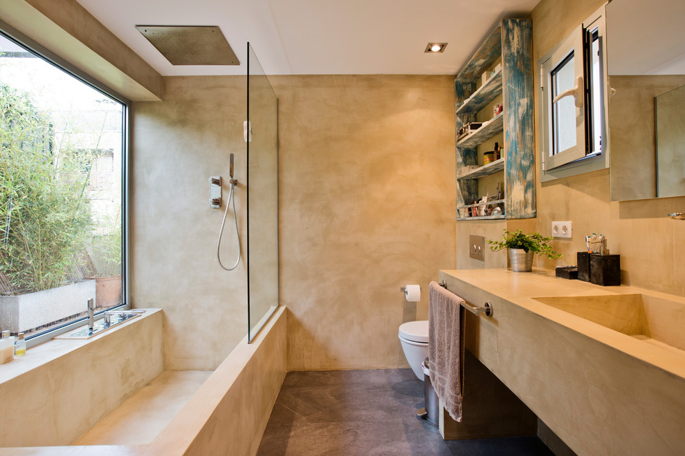 Foto di una stanza da bagno design con ante beige, vasca/doccia, lavabo integrato, vasca ad angolo, pareti beige, pavimento in cemento, pavimento marrone, doccia aperta e top beige