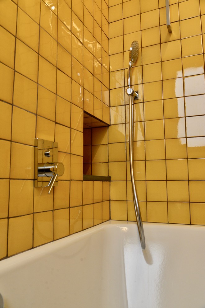 Idée de décoration pour une salle de bain principale urbaine de taille moyenne avec un placard en trompe-l'oeil, des portes de placard blanches, une baignoire posée, WC suspendus, un carrelage jaune, des carreaux de céramique, un mur jaune, sol en béton ciré, un lavabo encastré, un plan de toilette en bois, un sol gris et un plan de toilette marron.