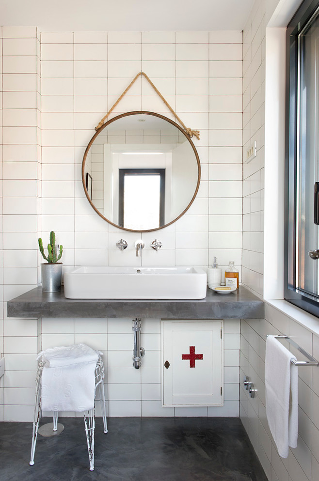 Modelo de cuarto de baño nórdico de tamaño medio con paredes blancas, suelo de cemento, lavabo sobreencimera, suelo negro y encimeras grises