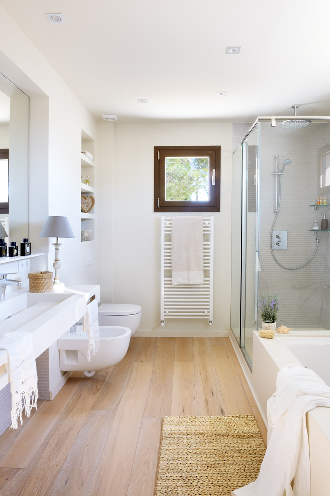 Inredning av ett lantligt mellanstort en-suite badrum, med ett badkar i en alkov, en hörndusch, en bidé, vita väggar, mellanmörkt trägolv, ett väggmonterat handfat, brunt golv och dusch med skjutdörr