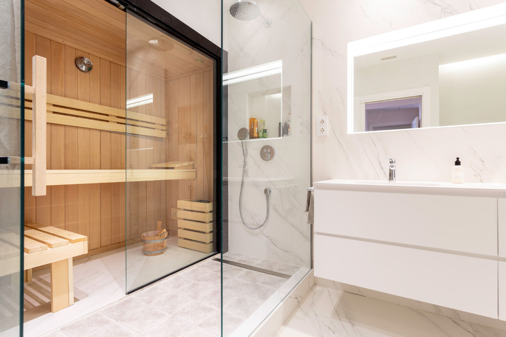 Example of a large trendy master white tile marble floor and white floor bathroom design in Barcelona with flat-panel cabinets, white cabinets, a two-piece toilet, white walls, a drop-in sink, a hinged shower door and white countertops