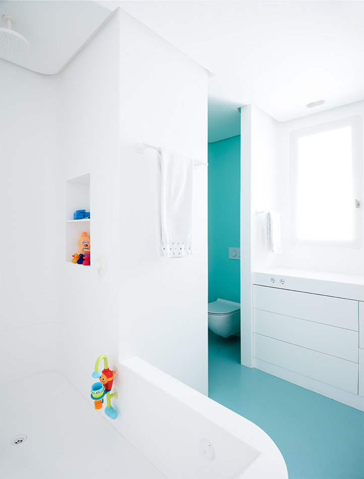 Foto de cuarto de baño infantil actual de tamaño medio con armarios con paneles lisos, puertas de armario blancas, bañera esquinera, combinación de ducha y bañera, sanitario de pared, paredes blancas y lavabo integrado