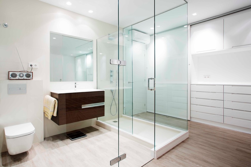 バルセロナにある高級な広いコンテンポラリースタイルのおしゃれなバスルーム (浴槽なし) (オープン型シャワー、壁掛け式トイレ、白い壁、無垢フローリング、一体型シンク) の写真