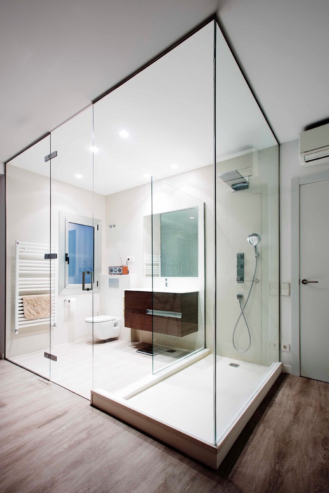 This is an example of a small contemporary shower room bathroom in Barcelona with flat-panel cabinets, dark wood cabinets, dark hardwood flooring, a wall mounted toilet and white walls.