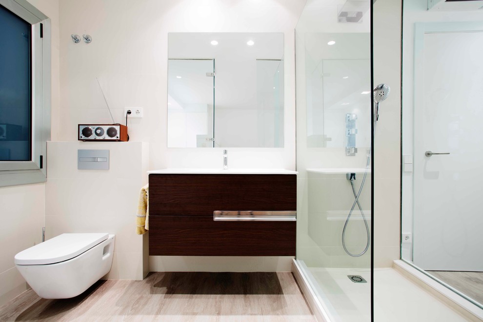 Immagine di una stanza da bagno con doccia design di medie dimensioni con consolle stile comò, ante in legno bruno, doccia aperta, WC sospeso, pareti bianche, parquet chiaro e lavabo integrato
